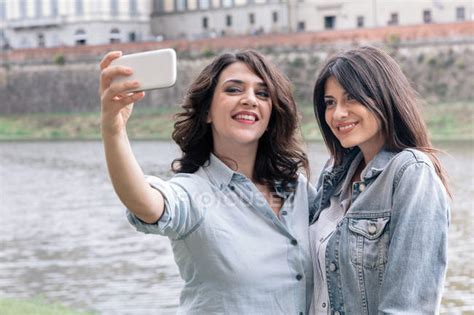 Lesbian Couple Using Smartphone To Take Selfie Next To Arno River Florence Tuscany Italy