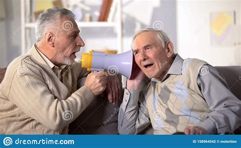 Senior Man Shouting Bullhorn To Deaf Friend Old Aged Health Deafness