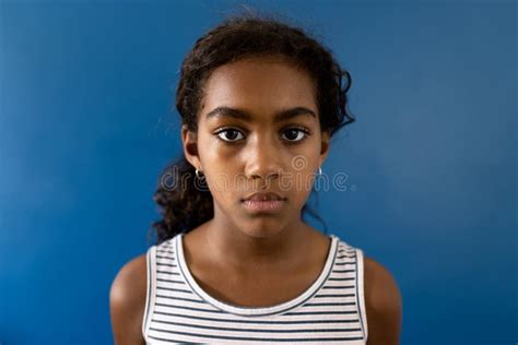 Portrait Of Sad Biracial Girl Wearing Striped Dress On Blue Background