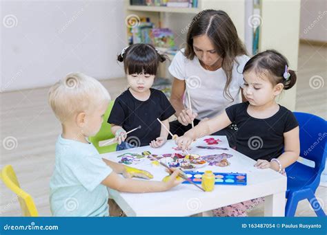 Nursery Kids Learning To Paint With Their Teacher Stock Photo Image