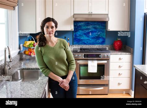 A Woman Relaxes In Her Kitchen And Leans Against The Kitchen Counter