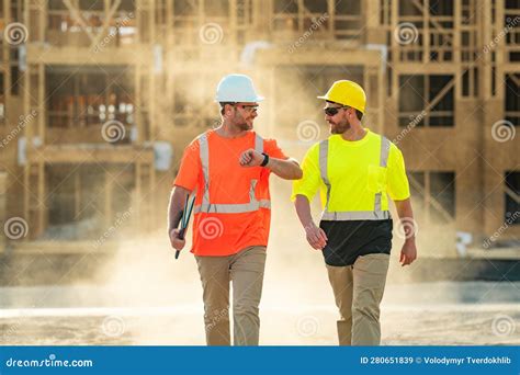Two Builders In A Hard Hat Is Busy Working On A Construction Project At