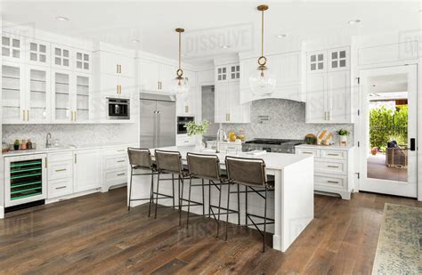 Kitchen island with built in seating might look like a weird idea for your kitchen, but if you have enough space you need to consider this option. Beautiful white kitchen in new luxury home, with waterfall island - Stock Photo - Dissolve