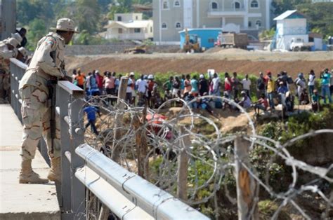 In Pictures A Member Of The Dominican Special Unit Border L Looks At Haitians Stranded On The