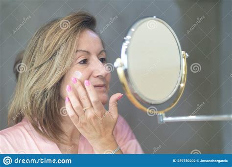 Senior White Woman Applying Moisturizer For Skin Care On Her Face