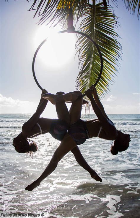 Two Women Doing Acrobatic Tricks On The Beach In Front Of Palm Trees