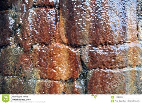 Close Up Texture Of Wet Brown Stone Wall With Dripping Water Reflecting