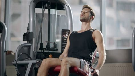 Fitness Man Training Legs On Sport Machine In Modern Gym Club Athlete