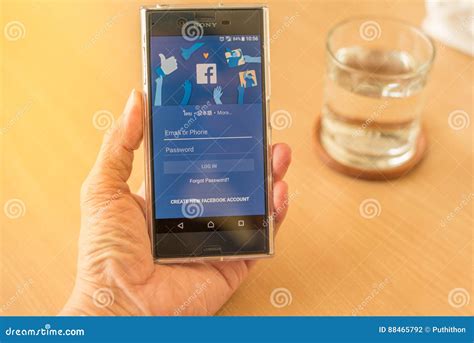 Hand Holding Mobile Phone With Facebook Application Editorial