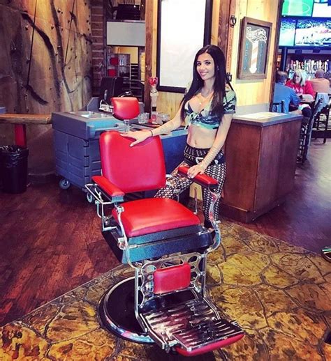 A Woman Sitting In A Red Chair At A Barbershop Posing For The Camera