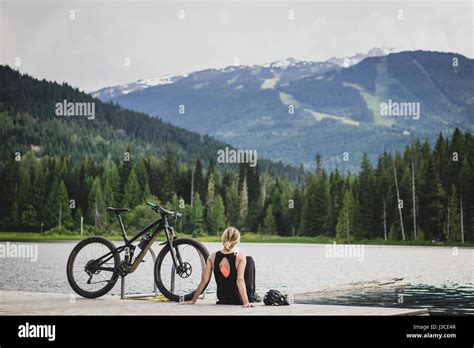 Blonde Girl Sitting On The Lost Lake Dock In Whistler Bc Canada With