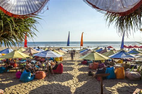 Indonesia Bali Denpasar Tourists Under Colorful Sunshades At Kuta