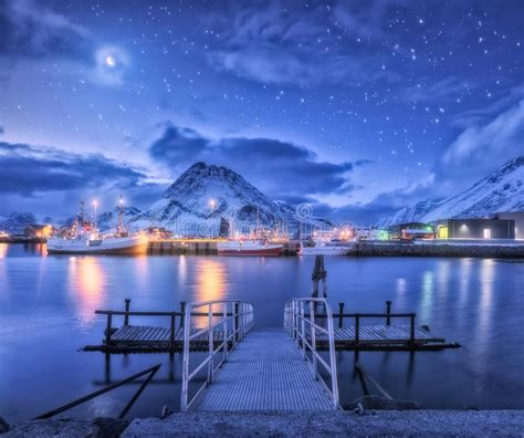 Fishing Boats Near Pier On The Sea And Snowy Mountains At Night Stock