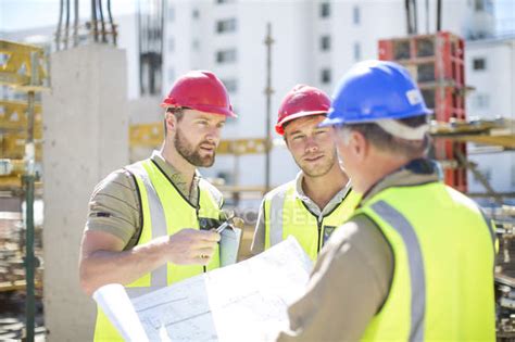 Construction Workers Discussing Building Plans In Construction Site