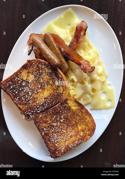A Mouth Watering Meal Of Fluffy French Toast Crispy Bacon Sausages