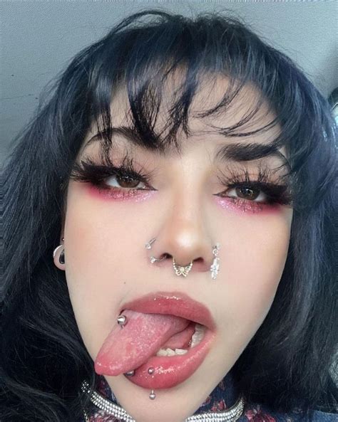 A Woman With Black Hair And Piercings Sticking Her Tongue Out