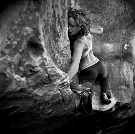 A Woman Climbing Up The Side Of A Large Rock With Her Hands On Her Hips