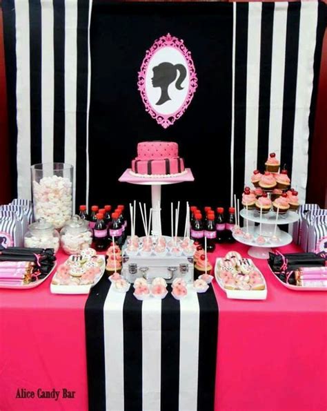 A Pink And Black Table Topped With Cakes And Cupcakes