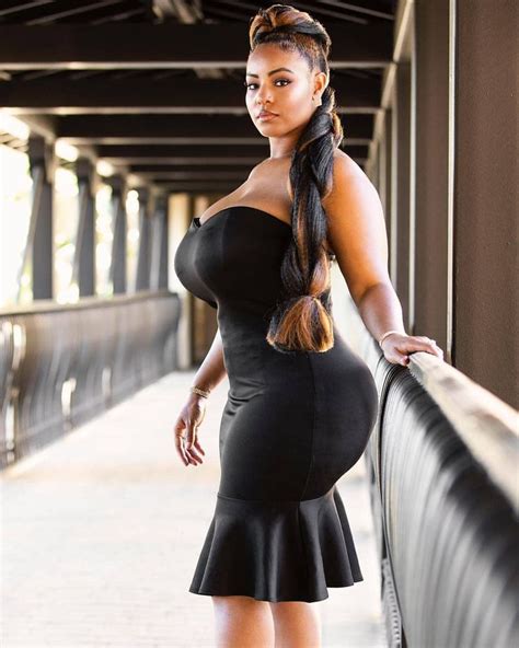 A Woman In A Black Dress Is Standing On A Bridge And Posing For The Camera