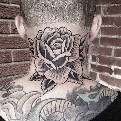 A Man With A Rose Tattoo On His Back Neck And Neck Is Standing In Front Of A Brick Wall