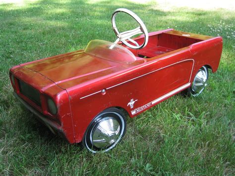 An Old Fashioned Red Pedal Car Sitting In The Grass With Its Steering