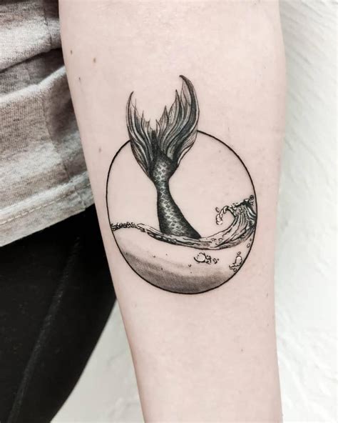 A Black And White Photo Of A Mermaid Tail Tattoo On The Right Arm With Waves Coming Out Of It