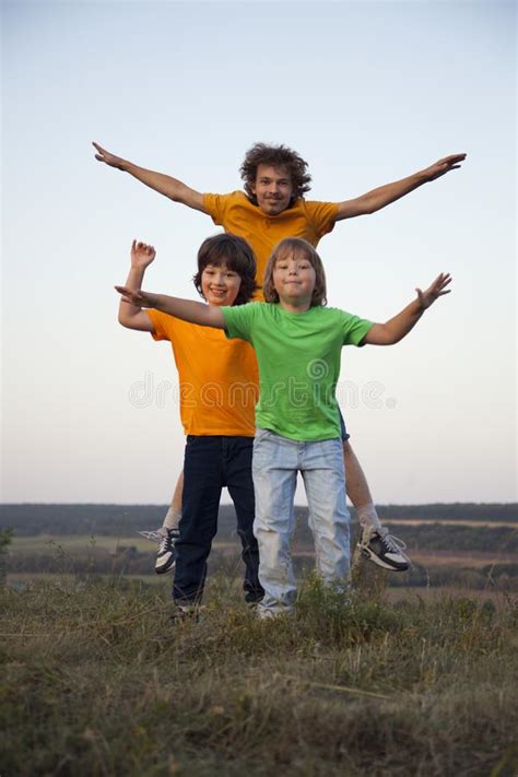 Children Playing Jumping On Summer Sunset Meadow Silhouetted Stock