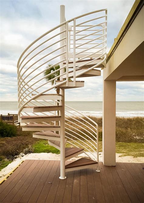 A galvanized steel outdoor spiral staircase has a metallic silver finish that fits well into industrial spaces. Exterior Stairs Design & Construction | Artistic Stairs