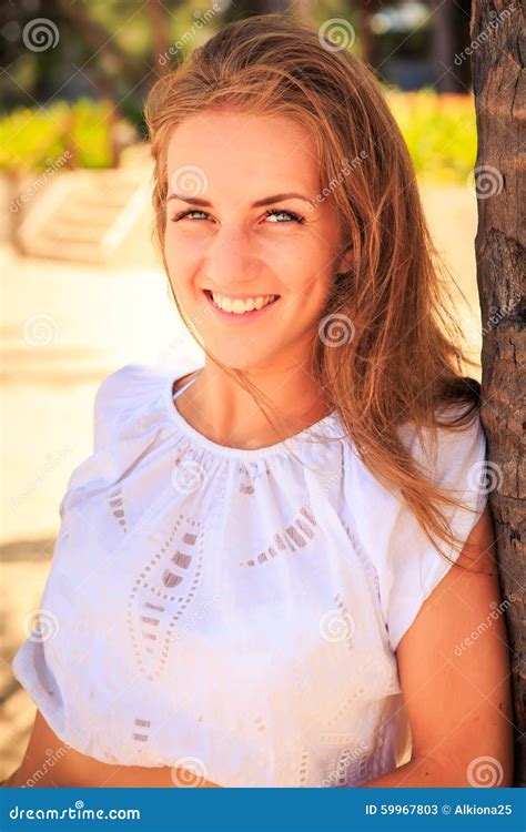 Portrait Of Blond Girl With Grey Eyes In White Against Plants Stock