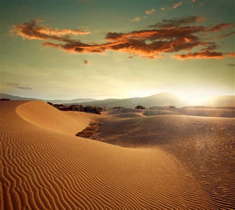 Sand Dunes At Sunset Light On Background Of Dramatic Sky Stock Photo