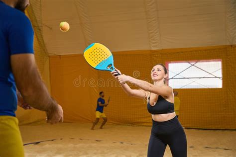 Woman Hitting Tennis Ball With Special Racket Next To Man Stock Photo