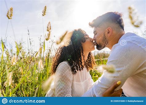 romance scene of mixed race couple in love kissing in backlight effect among flowers and high