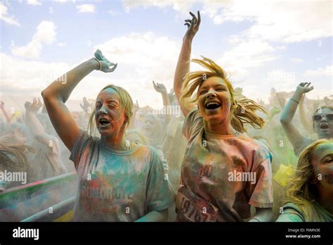 Young Women Jumping And Singing And Covered In Coloured Powder At Run