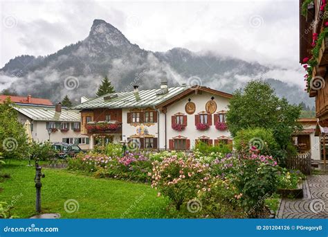 Classic Bavarian Village With Chalet Style Homes And Misty Mountains