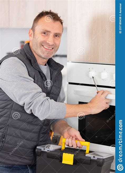 Repairman Examining Oven With Toolbox In Kitchen Stock Photo Image Of