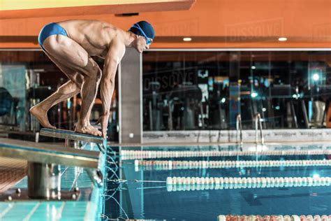 Swimmer Standing On Diving Board Ready To Jump Into Competition