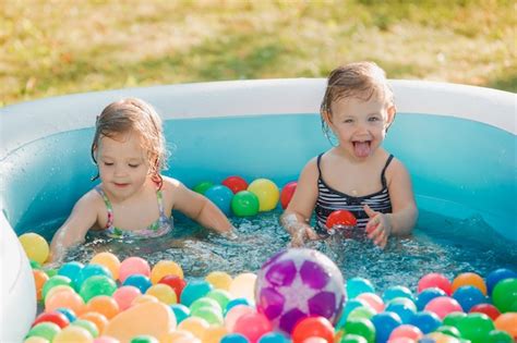 As Duas Meninas Brincando Com Brinquedos Na Piscina Inflável No Dia