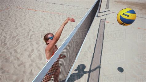 aerial close up happy caucasian girl smashes the ball over the net during a beach volleyball