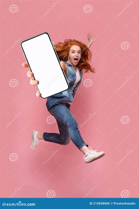 Excited Redhead Woman Having Fun Jumpingdemonstrating Mobile Phone