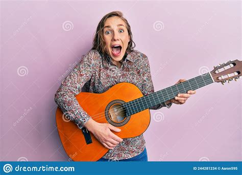 Young Blonde Woman Playing Classical Guitar Celebrating Crazy And