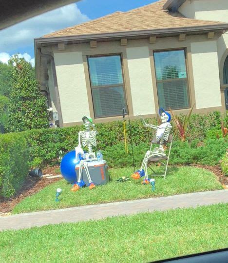 Two Skeletons Sitting In Front Of A House On The Lawn With Balls And Toys Around Them