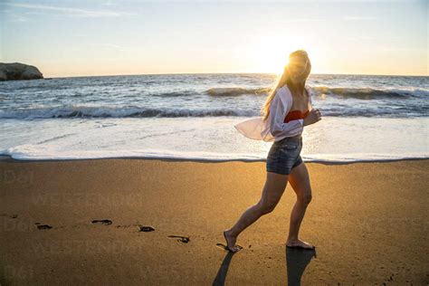 Teenage Girl Running On Beach At Sunset Cavf77245 Cavan Images