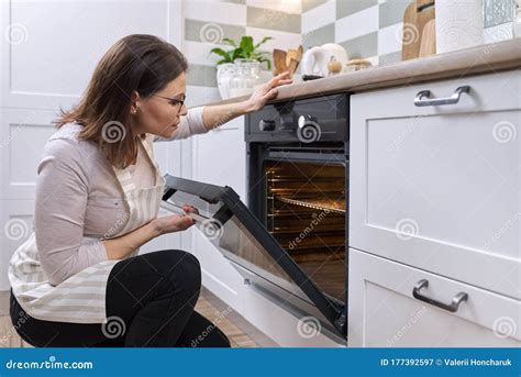 Mature Woman In Apron Near The Oven In The Kitchen Stock Image Image