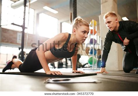 fitness woman exercising with fitness trainer in gym woman doing push ups exercise with her