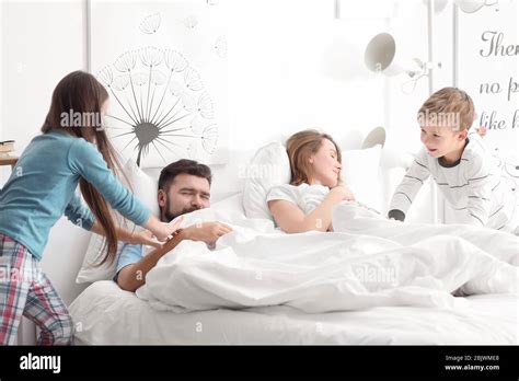 Children Waking Up Their Parents In Bedroom Stock Photo Alamy
