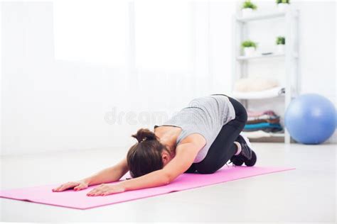 Fit Woman Bending Over On Mat Doing Pilates Exercise At Home In The
