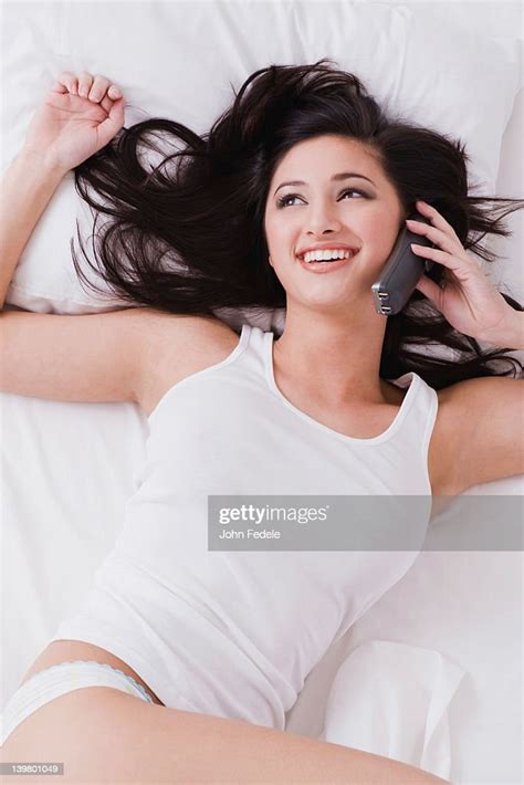 Alluring Mixed Race Woman Laying In Bed Talking On Telephone High Res