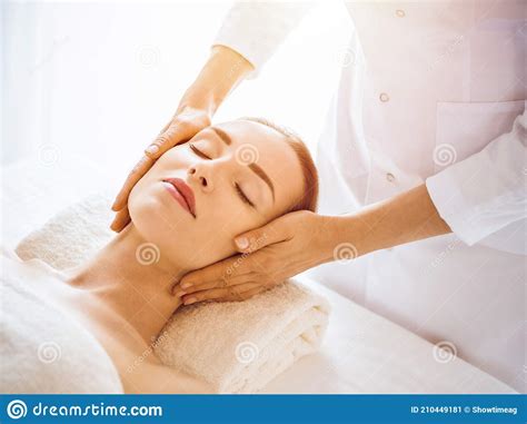 Beautiful Woman Enjoying Facial Massage With Closed Eyes In Sunny Spa Center Stock Image Image