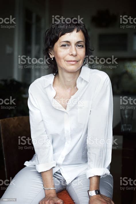 A Mature Woman Sitting While Smiling At The Camera Stock Photo