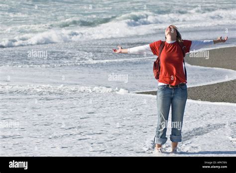 Happy Female Wading Through Water Of Tasman Sea On Empty West Coast